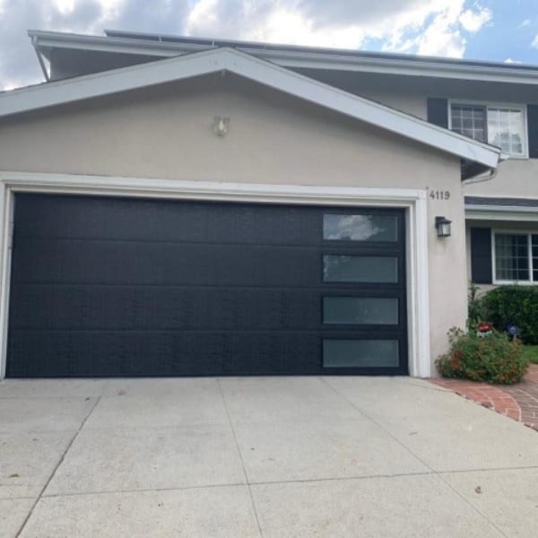 Emergency garage door repair service at residential home in the afternoon with technician working on the door