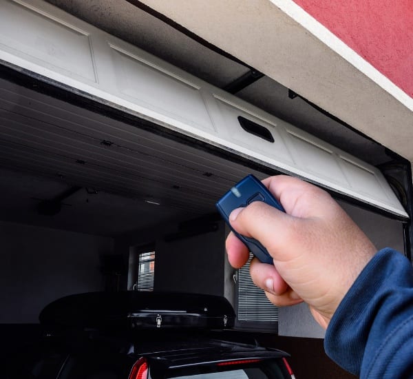 Remote control opens garage door for secure car storage in a residential area during daytime