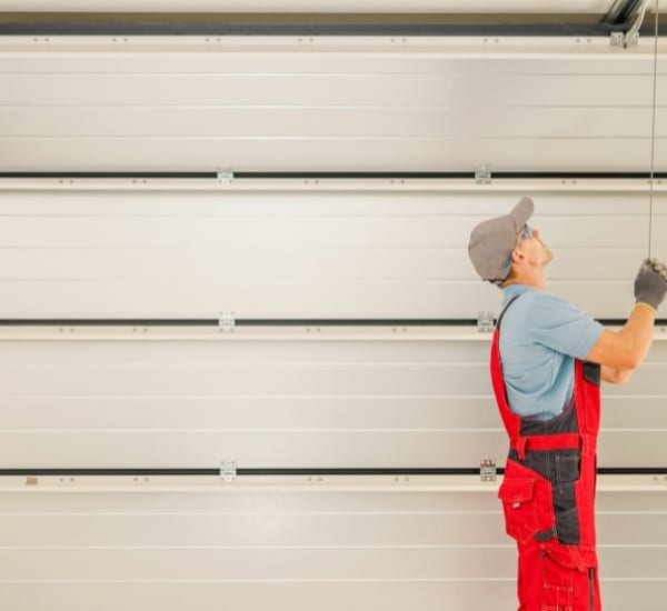 Worker installing garage door with attention to detail in residential garage at midday