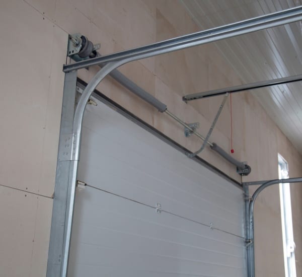 Modern garage door mechanism displayed in a workshop with metal tracks and pulleys