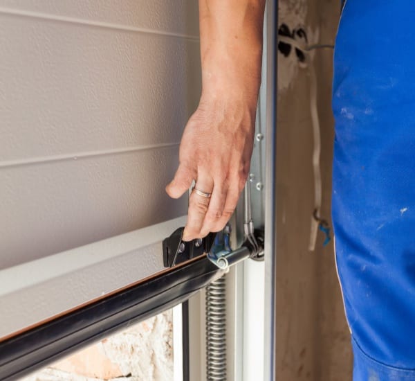 Hand adjusting garage door mechanism during installation in a home workshop