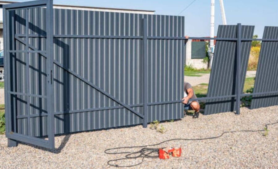 HOA technician inspecting sliding gate track for wear and rust during routine maintenance