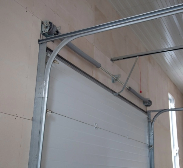 Modern garage door mechanism displayed in a workshop with metal tracks and pulleys