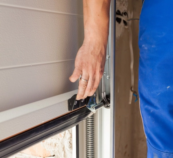 Hand adjusting garage door mechanism during installation in a home workshop
